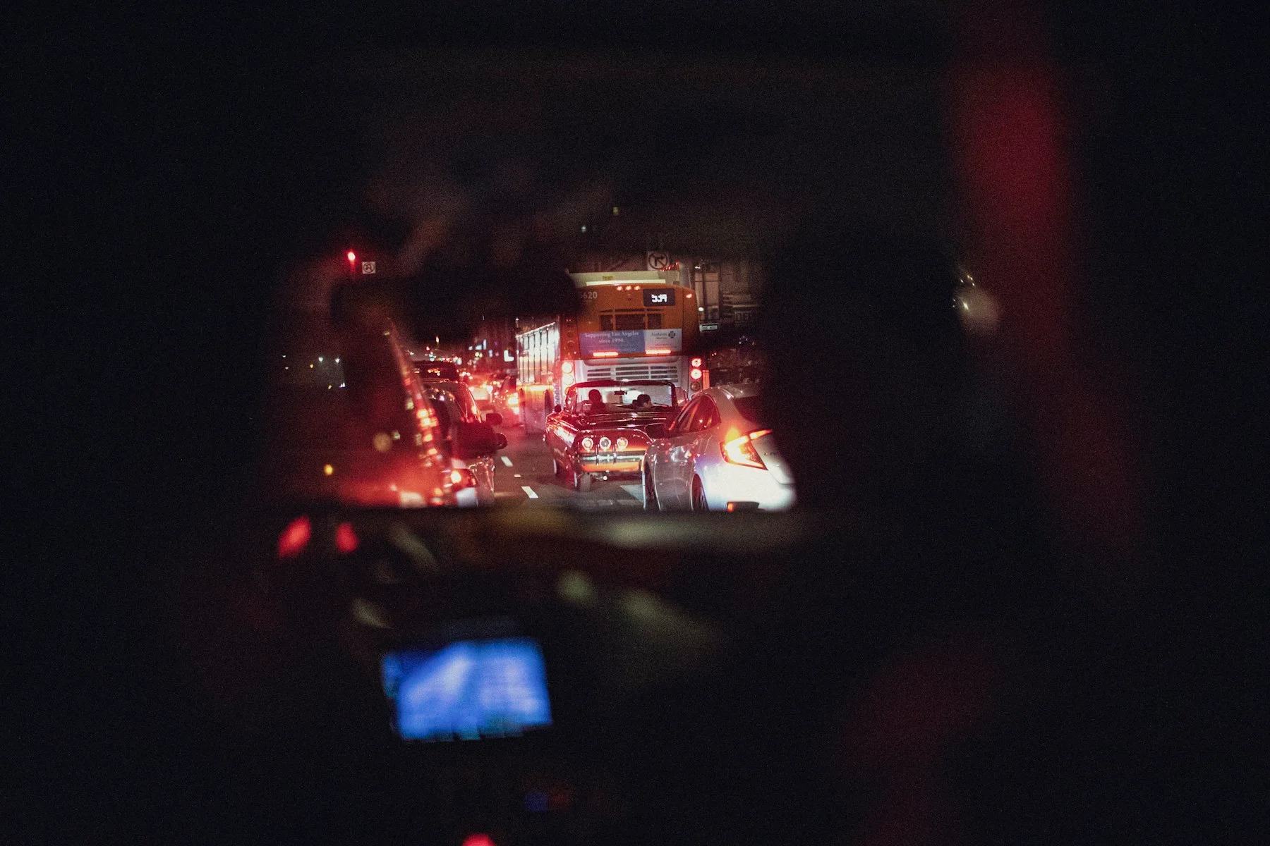 Night traffic seen through the windshield from a dark car interior
