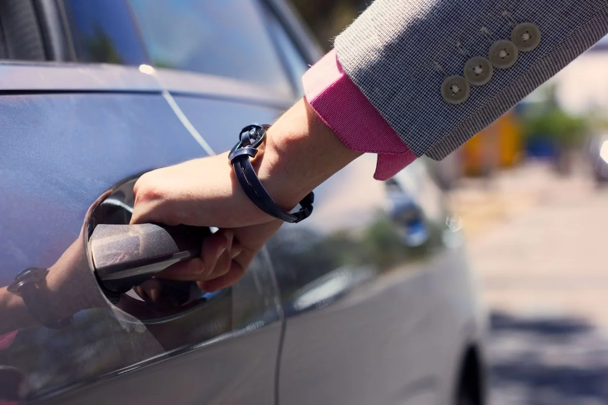 A hand opening a car door, illustrating a personal welcome